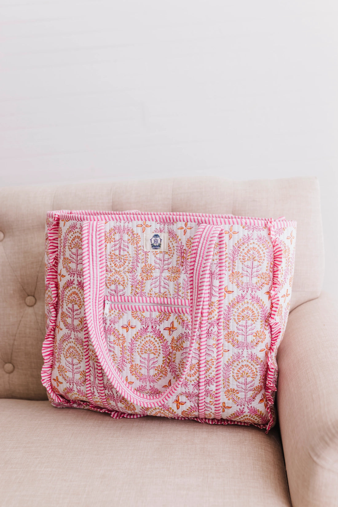 Pink patterned blanket draped over a beige couch