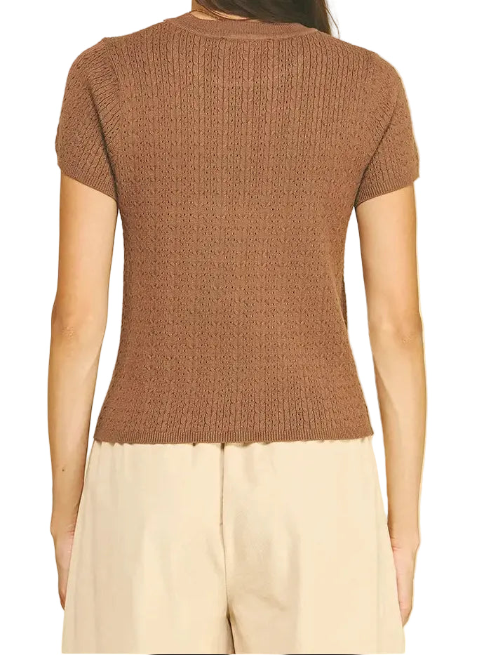 A woman shown from the back wearing a short-sleeve brown ribbed knit top and cream-colored pants, set against a solid white background.