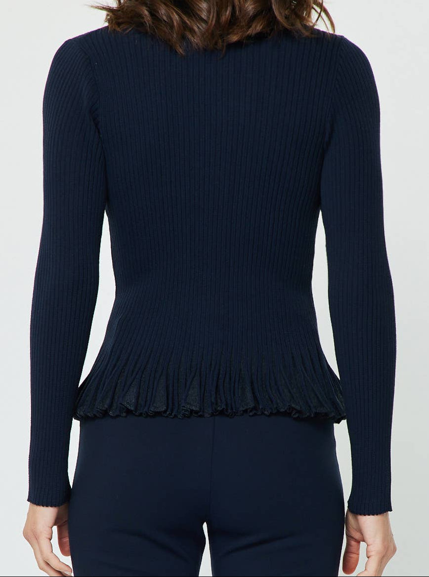 A woman viewed from the back wearing a dark navy ribbed long-sleeve top with a ruffled hem and matching dark navy bottoms, against a plain light gray studio background.