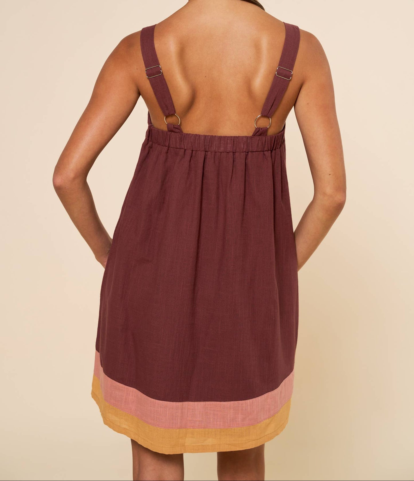 Woman wearing a maroon dress with a beige background