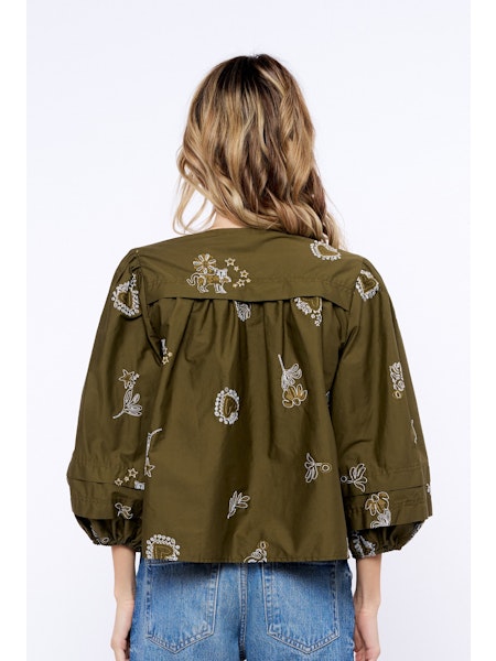 Person wearing an olive green embroidered jacket on a white background