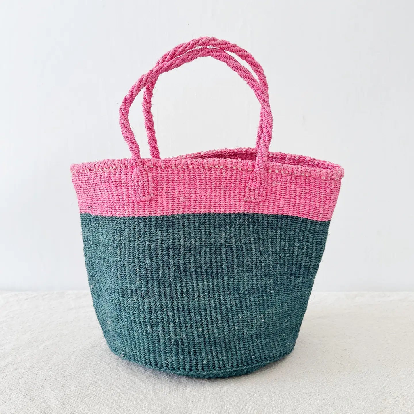 Woven basket with pink top and blue bottom on a white background