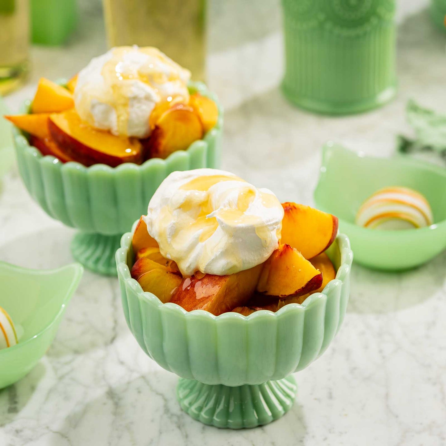 Green bowls filled with peach slices and whipped cream on a textured surface.