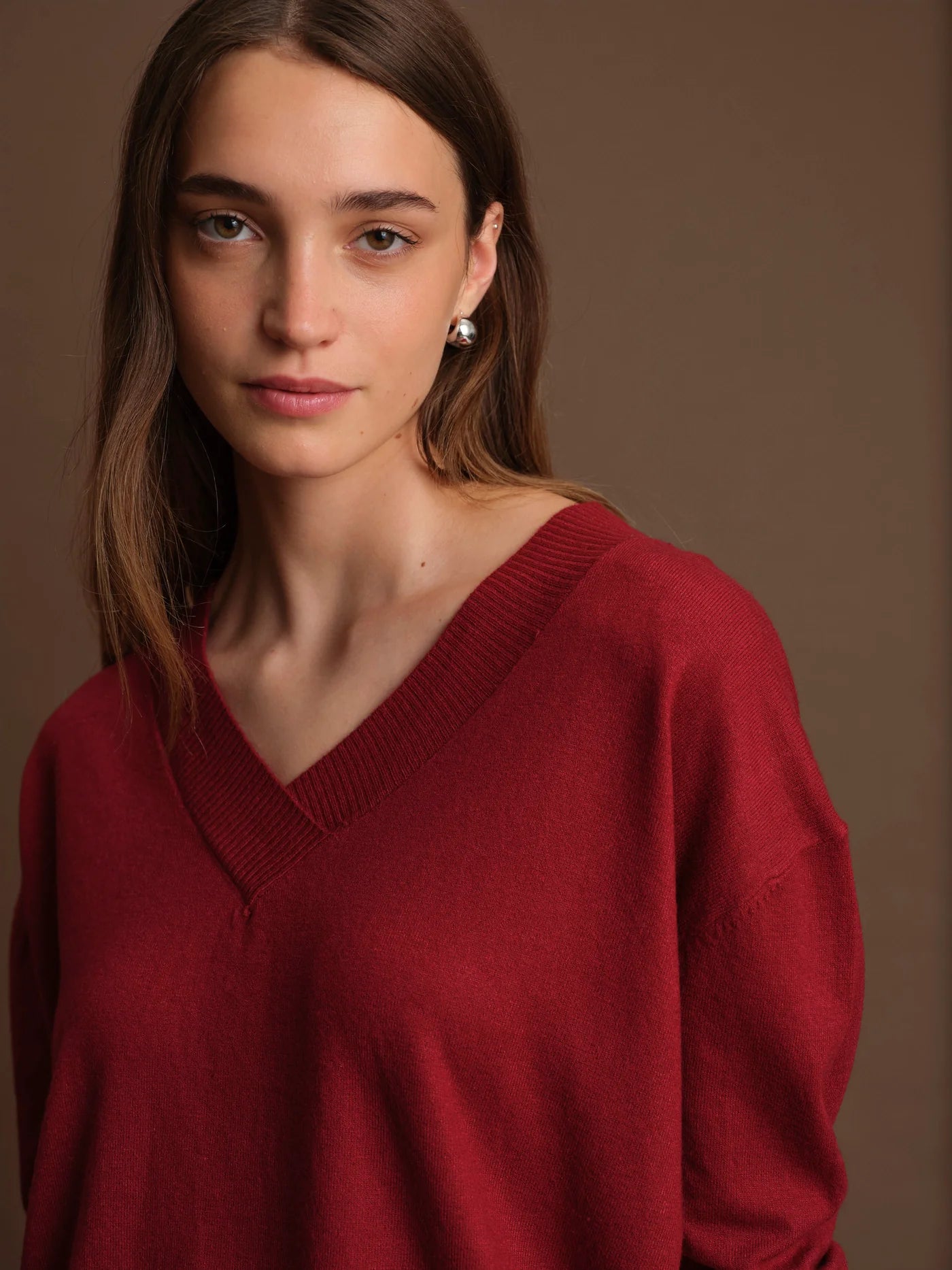 Woman wearing a red sweater against a brown background