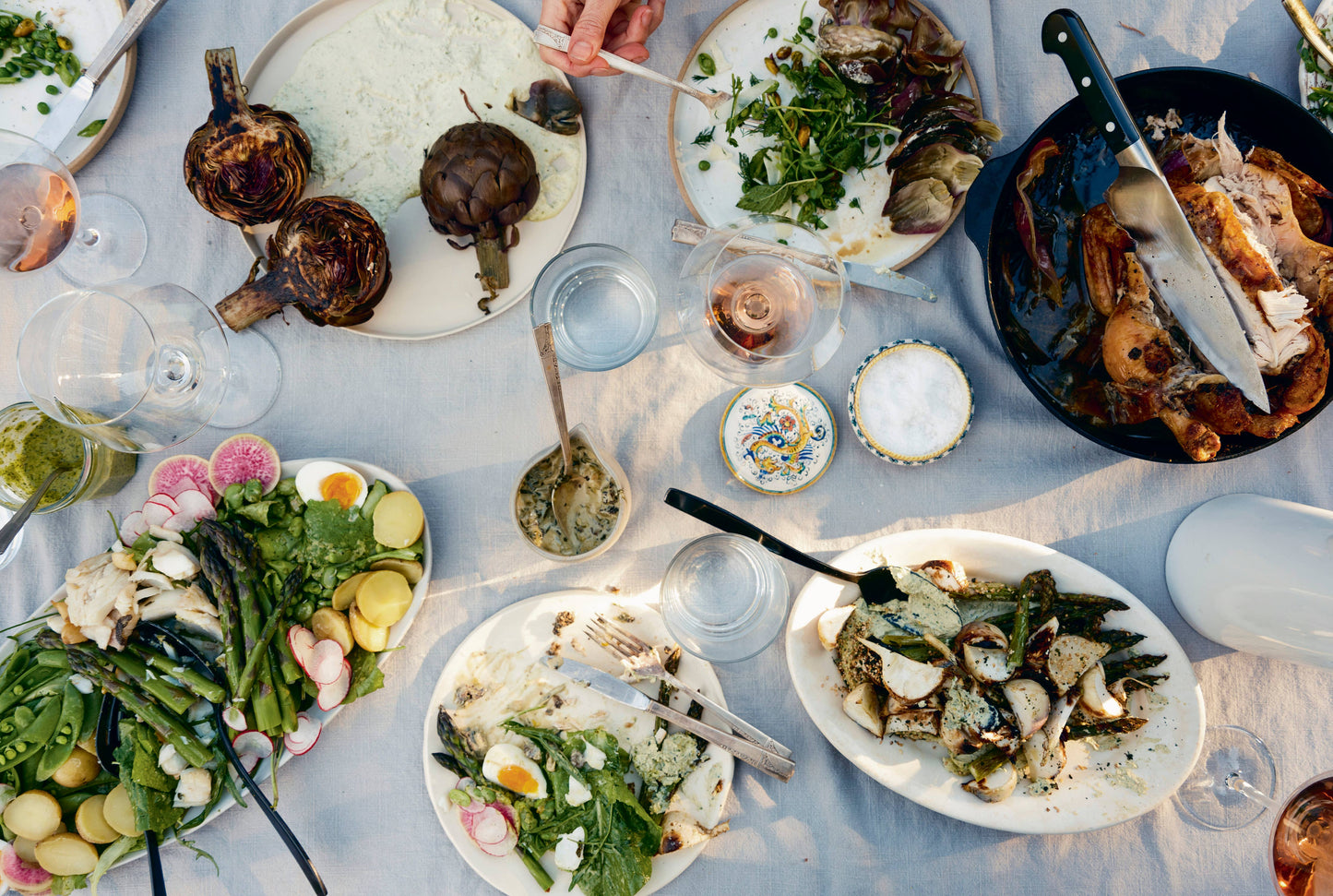 Diverse array of food on a table with various dishes and utensils.