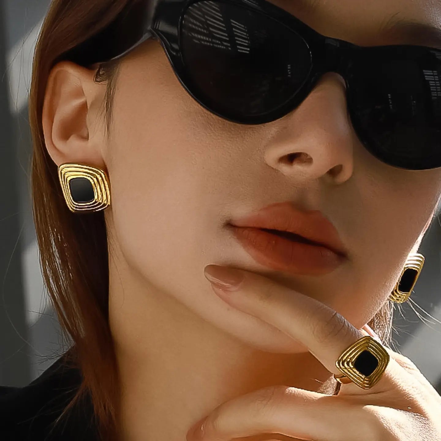 Close-up of a person wearing gold earrings with black centers.