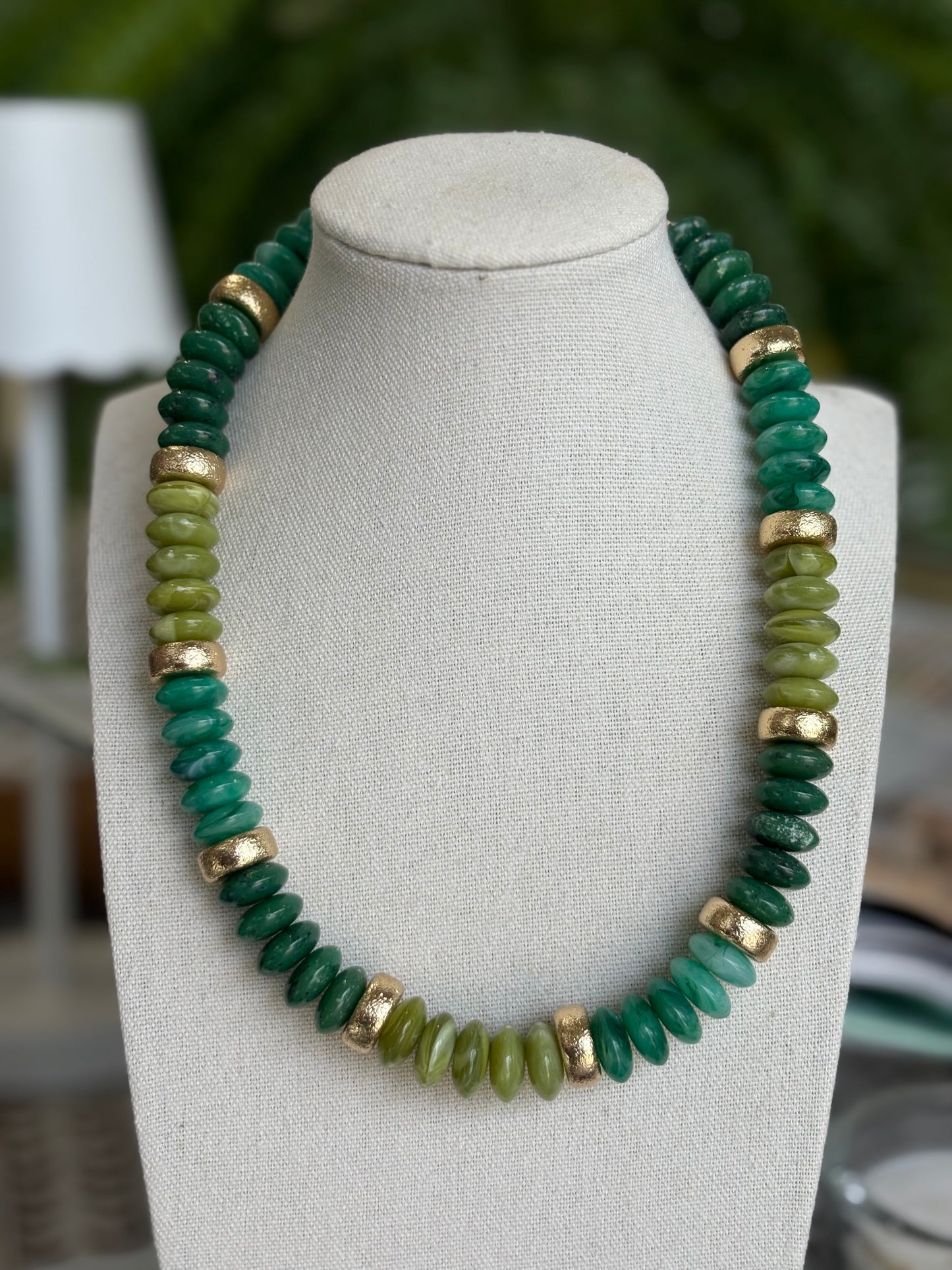 Green beaded necklace on a mannequin bust with a blurred background