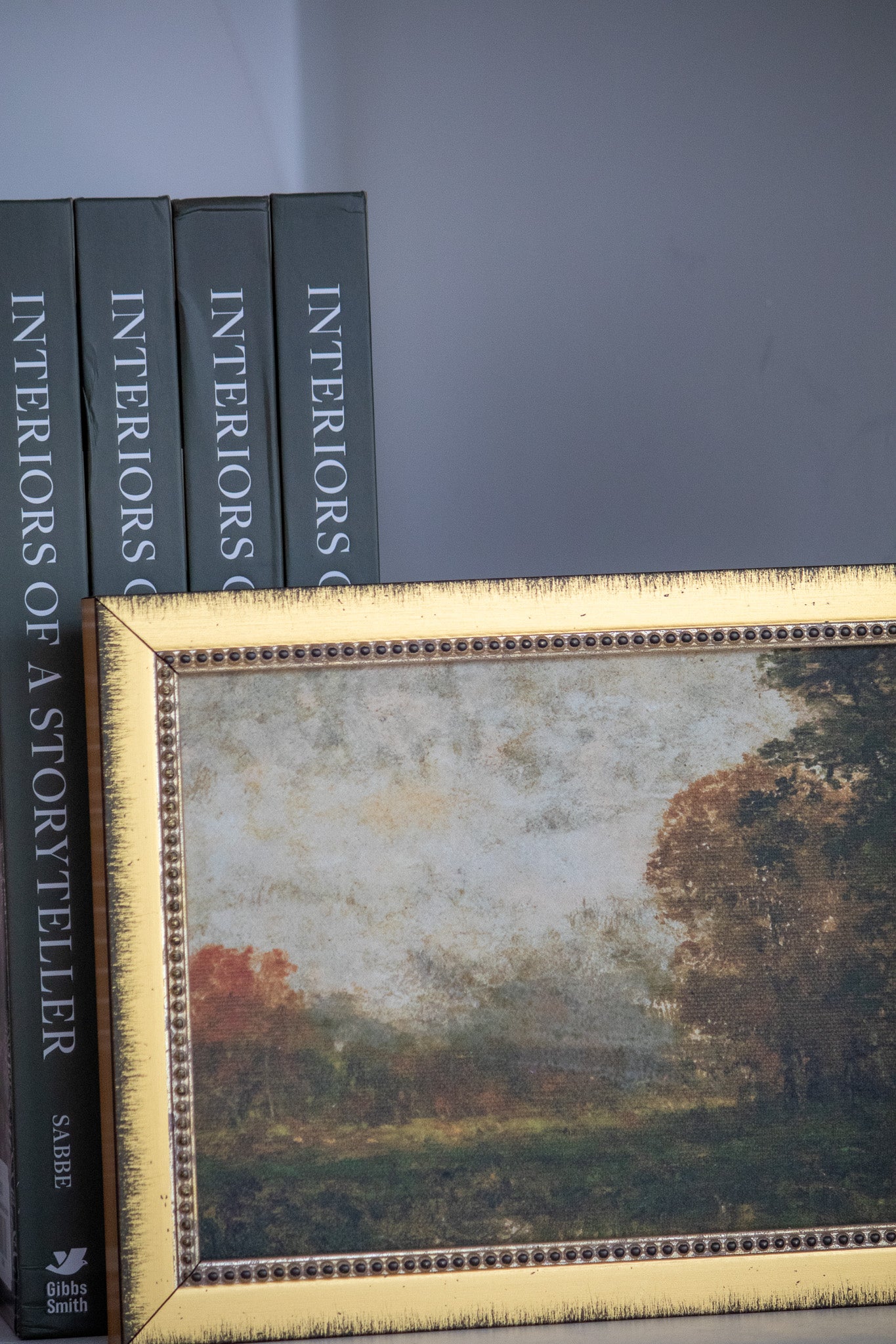 Framed artwork with 'Interiors of a Storyteller' books on a gray background