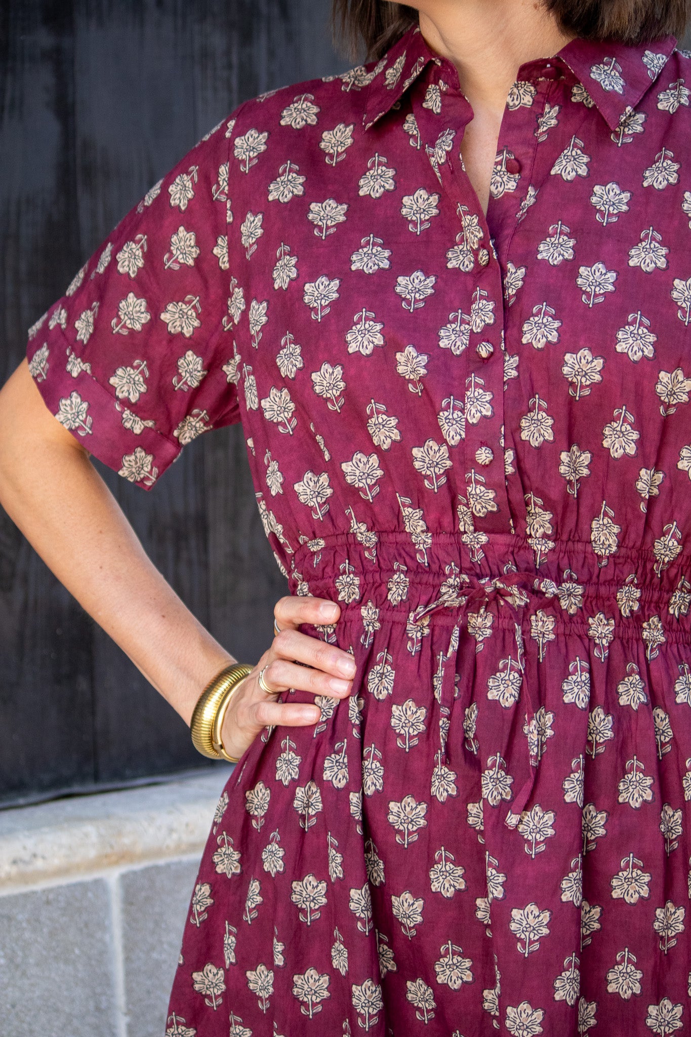 Maroon dress with floral pattern worn by a person against a dark background