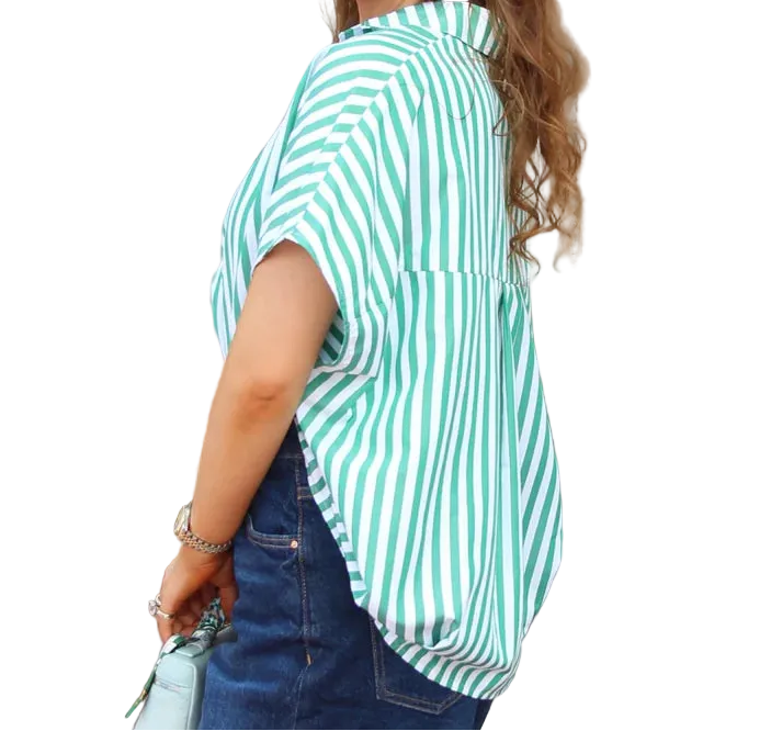 Woman wearing a green and white striped shirt and denim shorts standing outdoors.