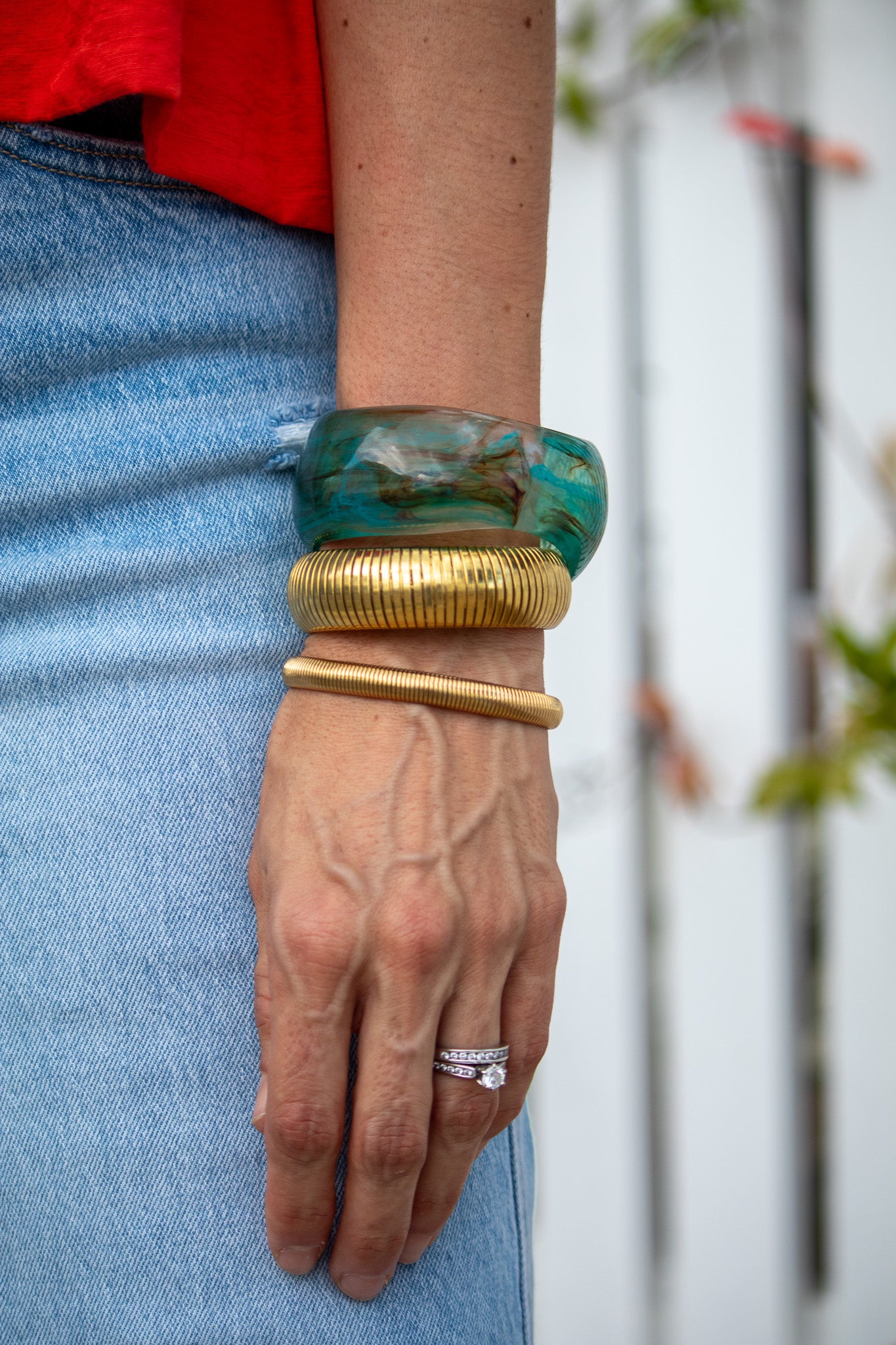Hand wearing gold and green bangles with a blurred background