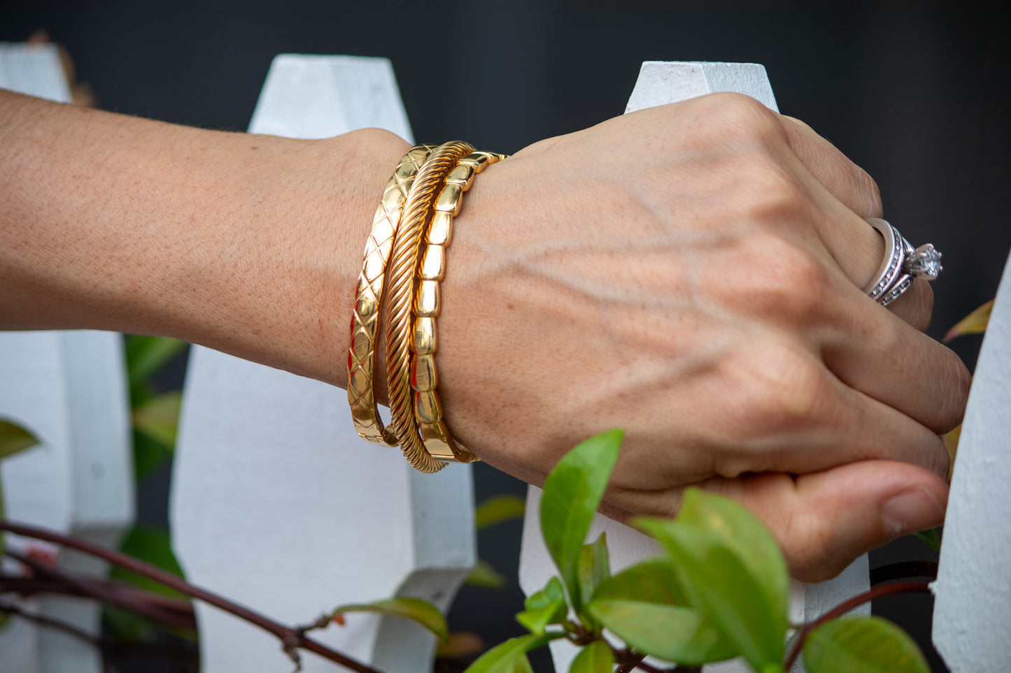 Hand wearing gold bracelets with a blurred background