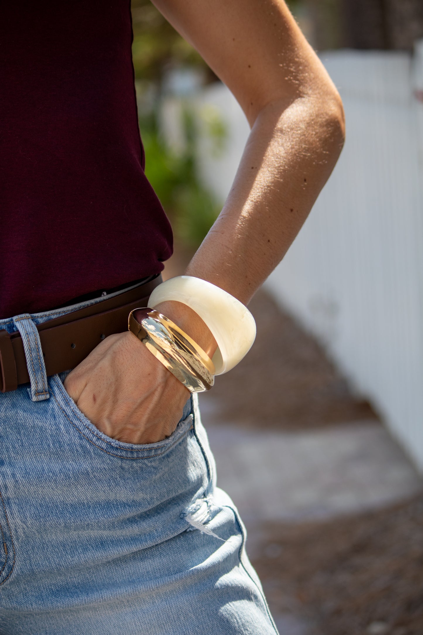 Person wearing a brown belt and light blue jeans with a blurred background