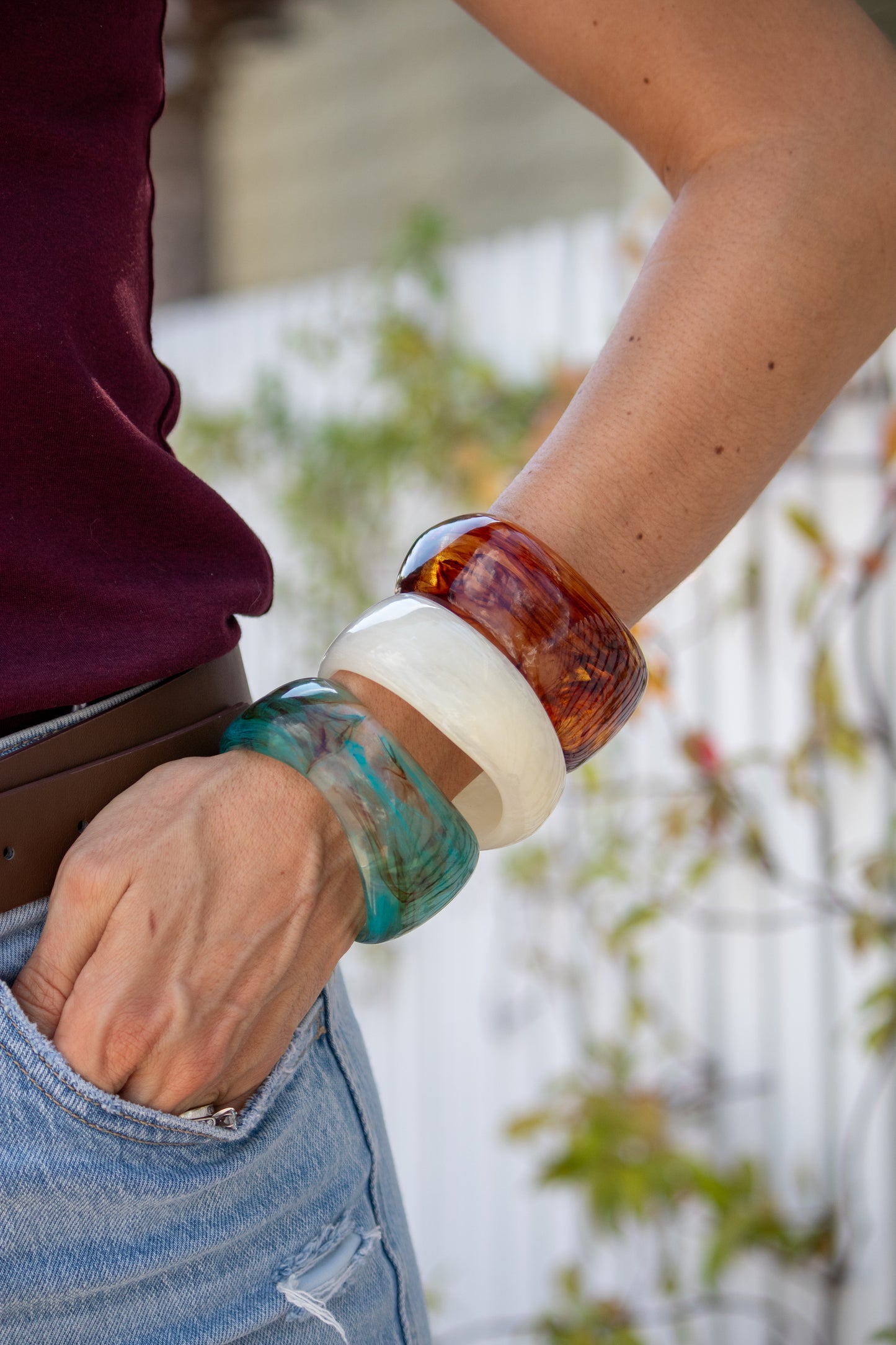 Close-up of a person's arm wearing colorful bracelets with a blurred background.