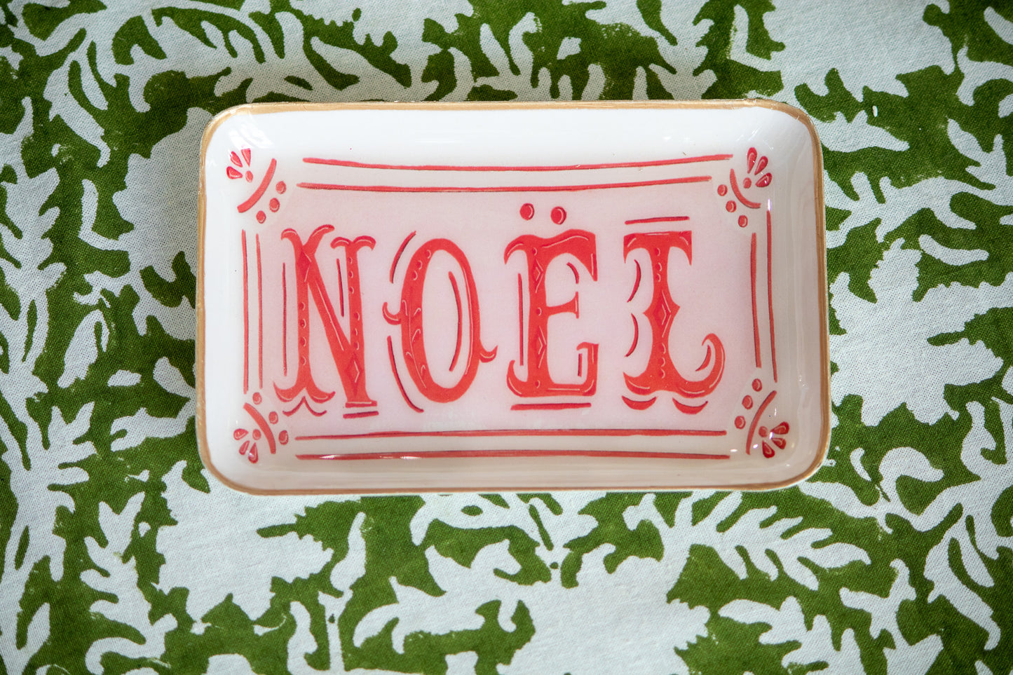 Decorative tray with 'NOEL' text on a green leafy tablecloth