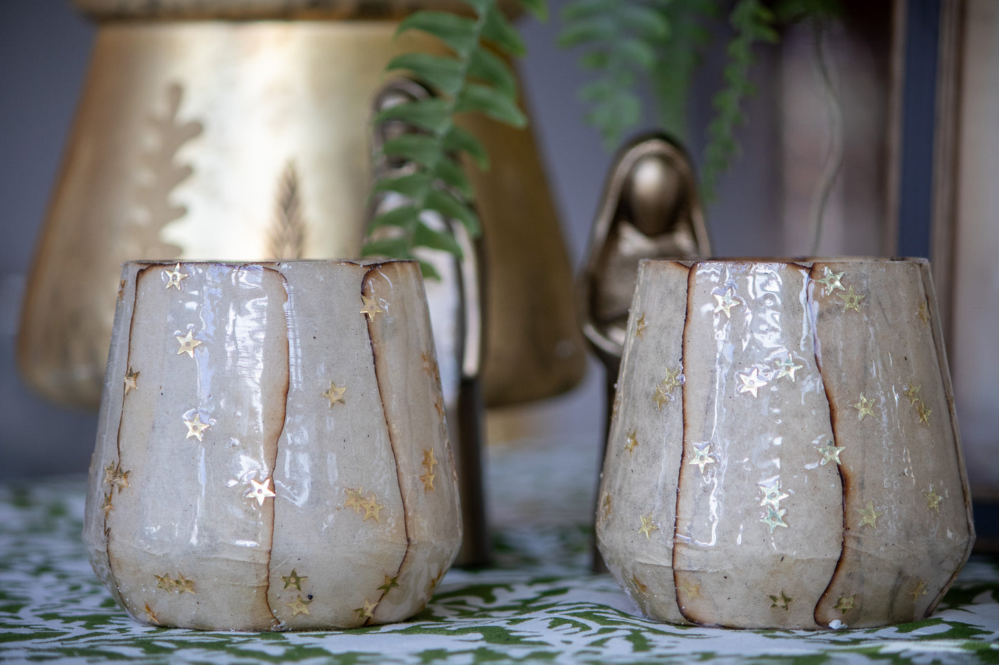 Two ceramic candle holders with star patterns on a decorative surface.