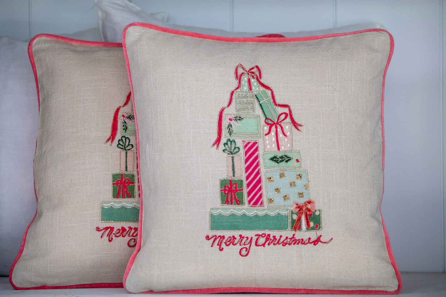 Decorative pillows with Christmas-themed embroidery on a neutral background