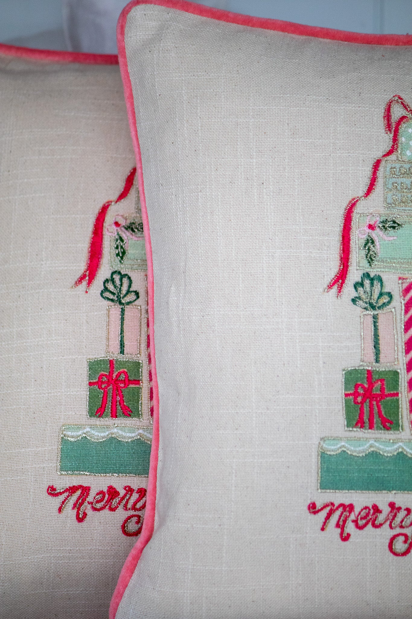 Decorative pillow with embroidered designs and 'Merry Christmas' text on a light background.