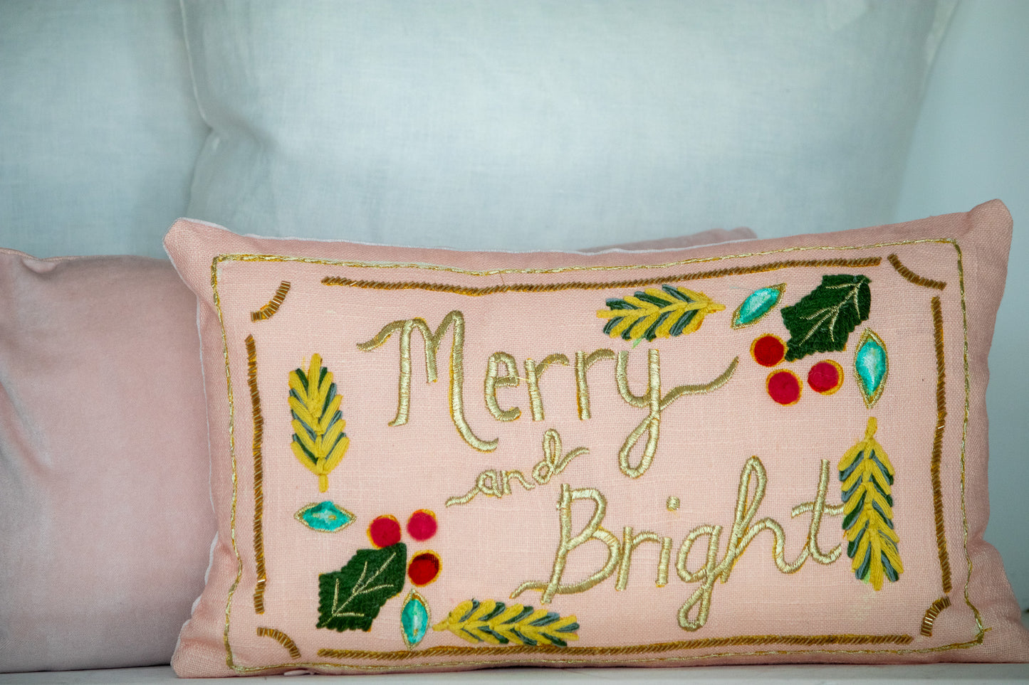 Decorative pillow with 'Merry and Bright' text and festive elements on a light background.