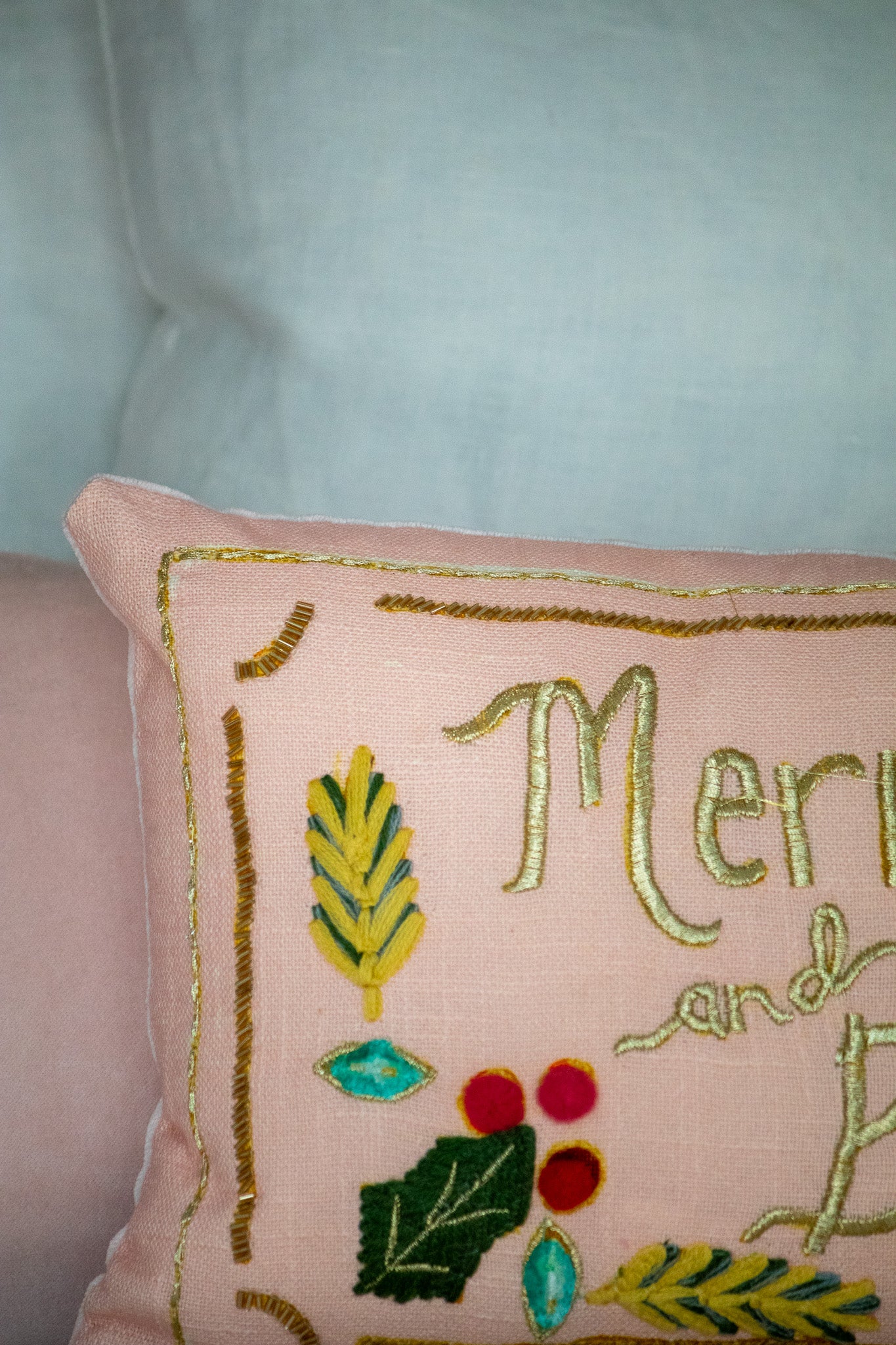Decorative pillow with embroidered text and festive elements on a light background
