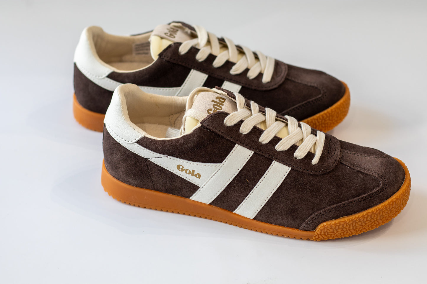Pair of brown and white sneakers with a visible brand logo on a light background