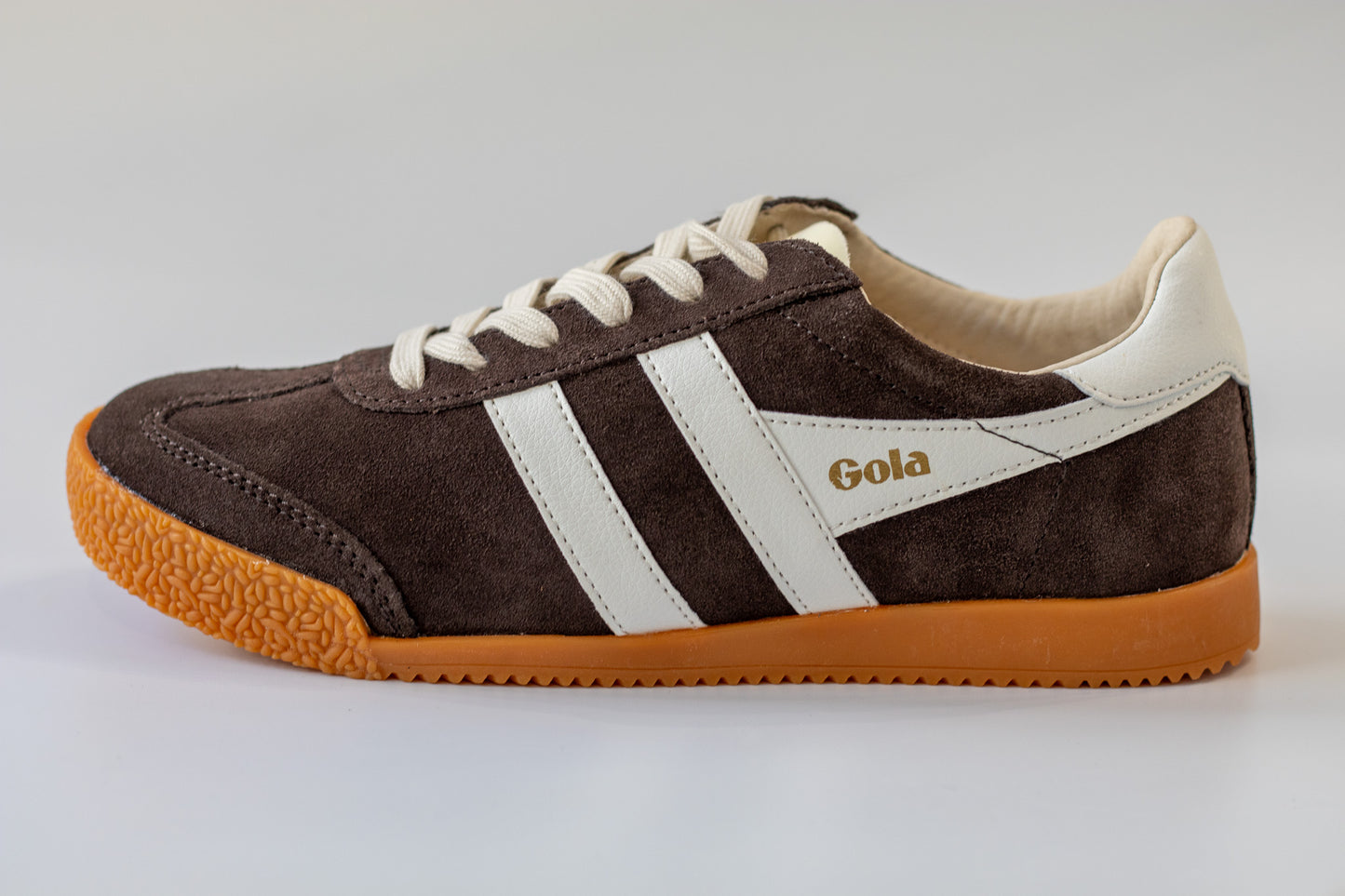Brown sneaker with white stripes and 'Gola' branding on a light gray background