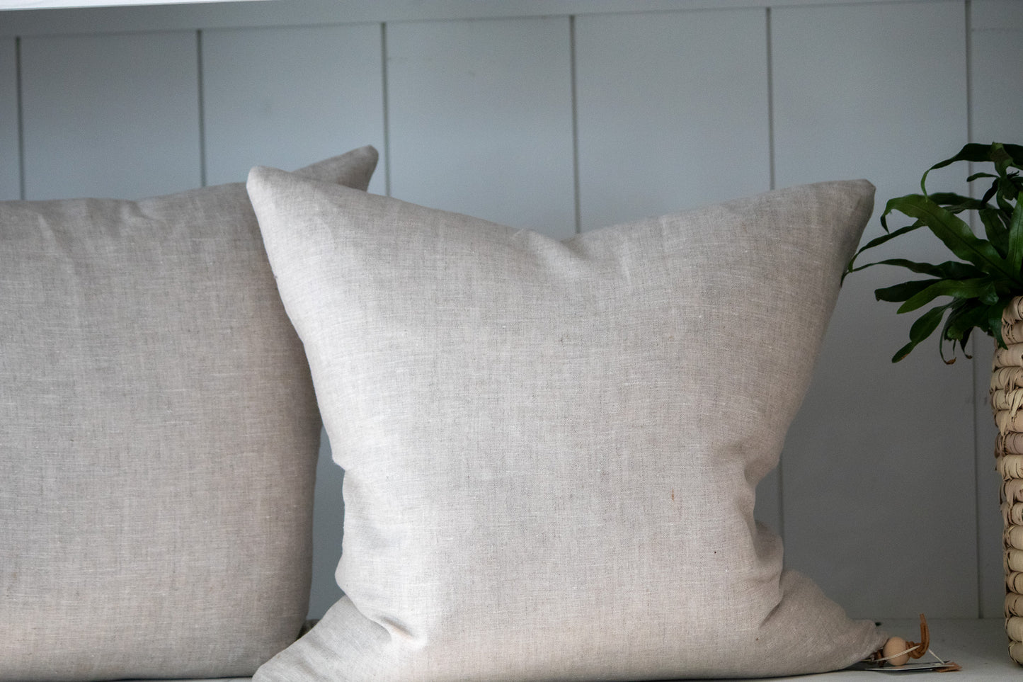Two beige pillows on a surface with a neutral background