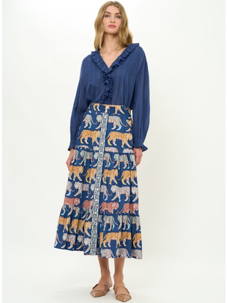 Woman wearing a blue blouse and patterned skirt with tigers on a white background