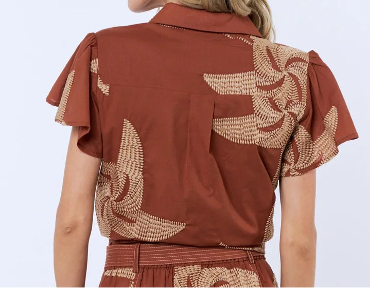 Woman wearing a brown dress with floral patterns on a white background