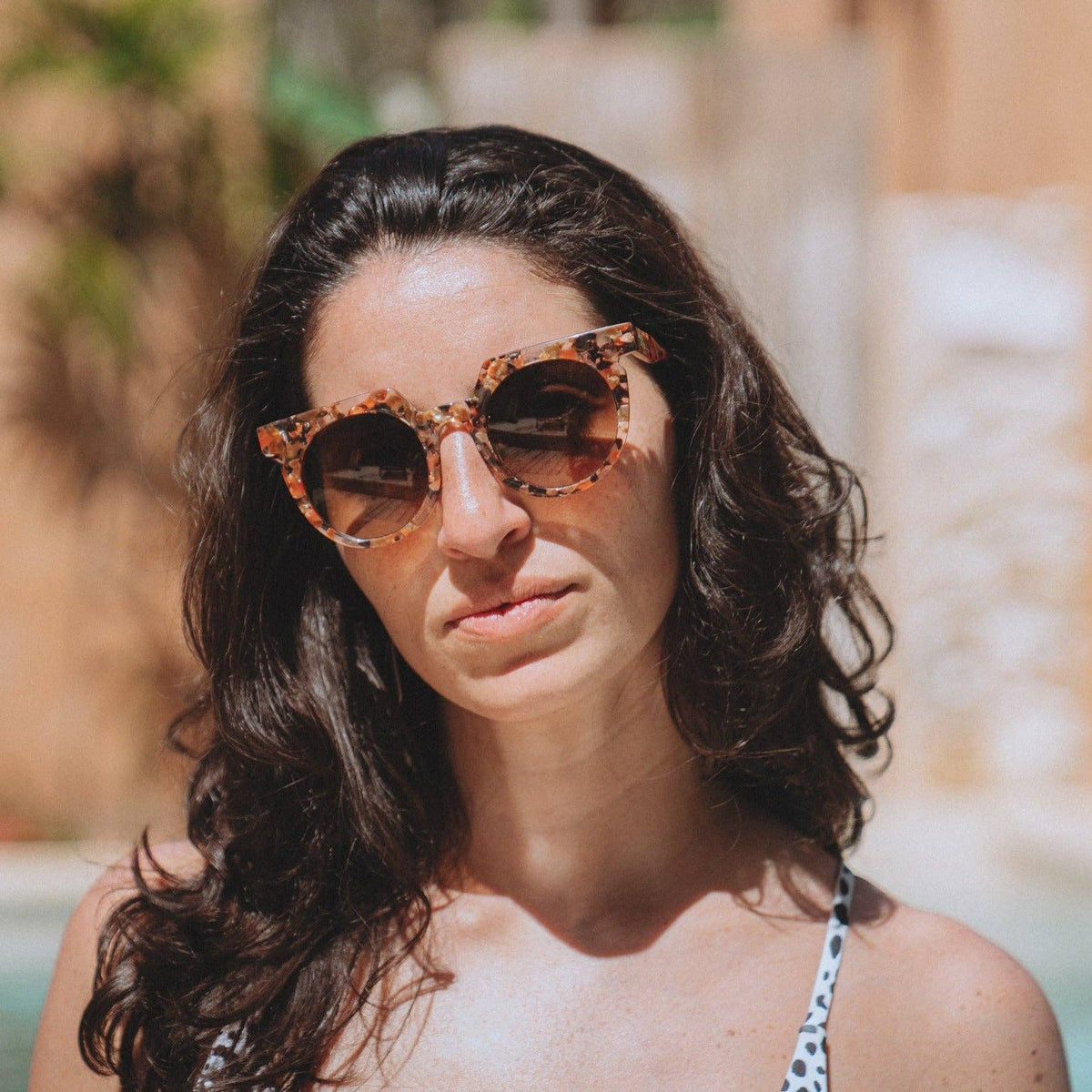 Woman wearing tortoiseshell sunglasses with a blurred outdoor background
