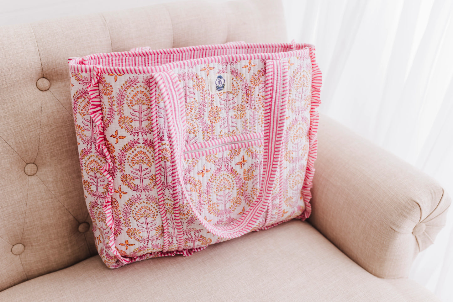 Pink and white patterned blanket draped over a beige couch