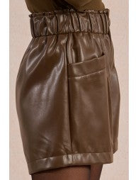 Brown leather skirt worn by a person on a beige background
