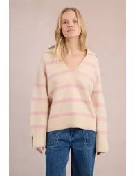 Woman wearing a striped sweater and jeans against a plain background