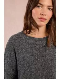 Woman wearing a dark gray sweater against a light pink background