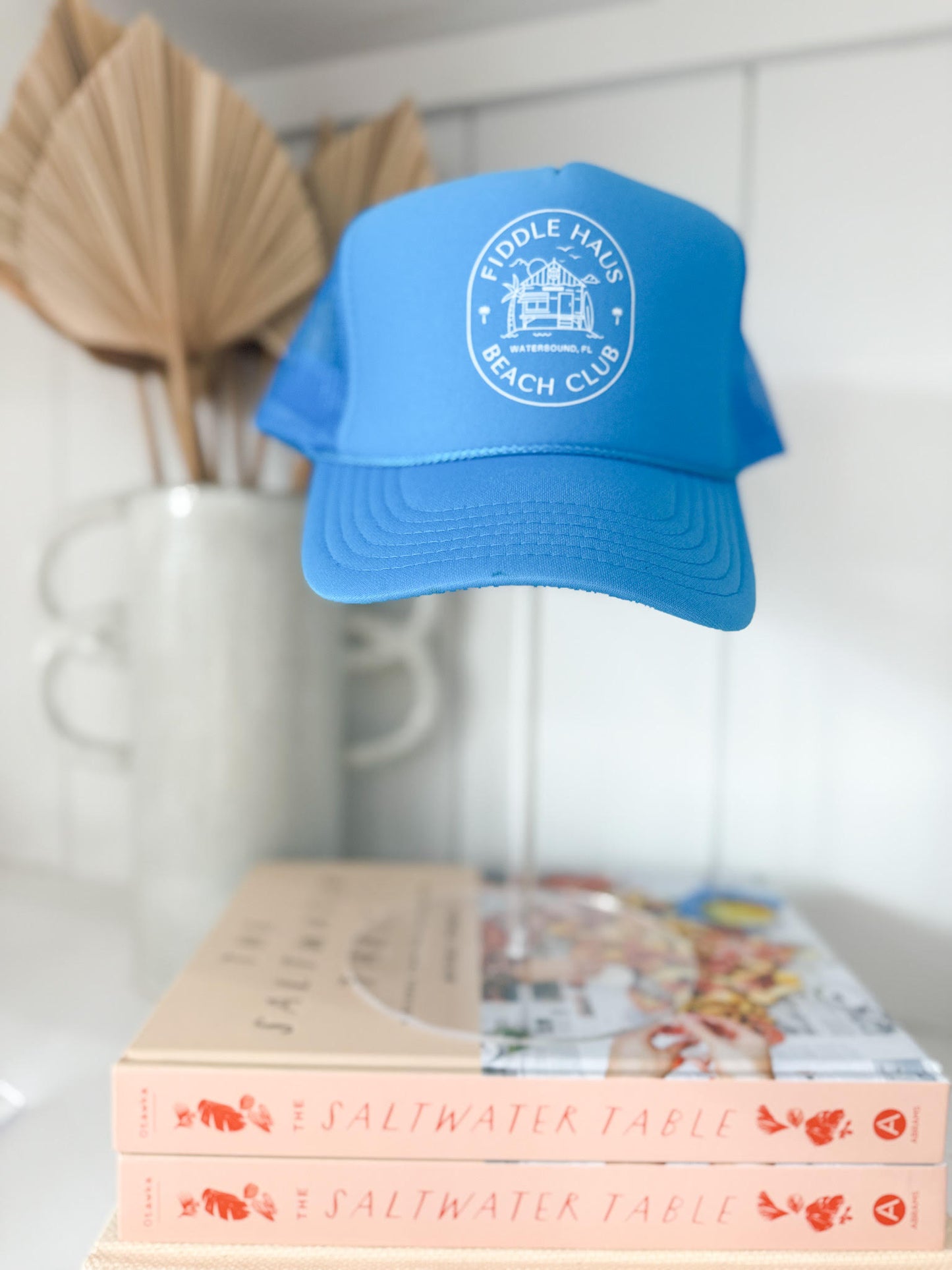 Blue cap with a logo on top of books against a white wall