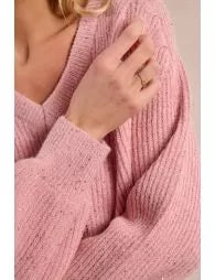 Close-up of a person wearing a pink knitted sweater with a blurred background