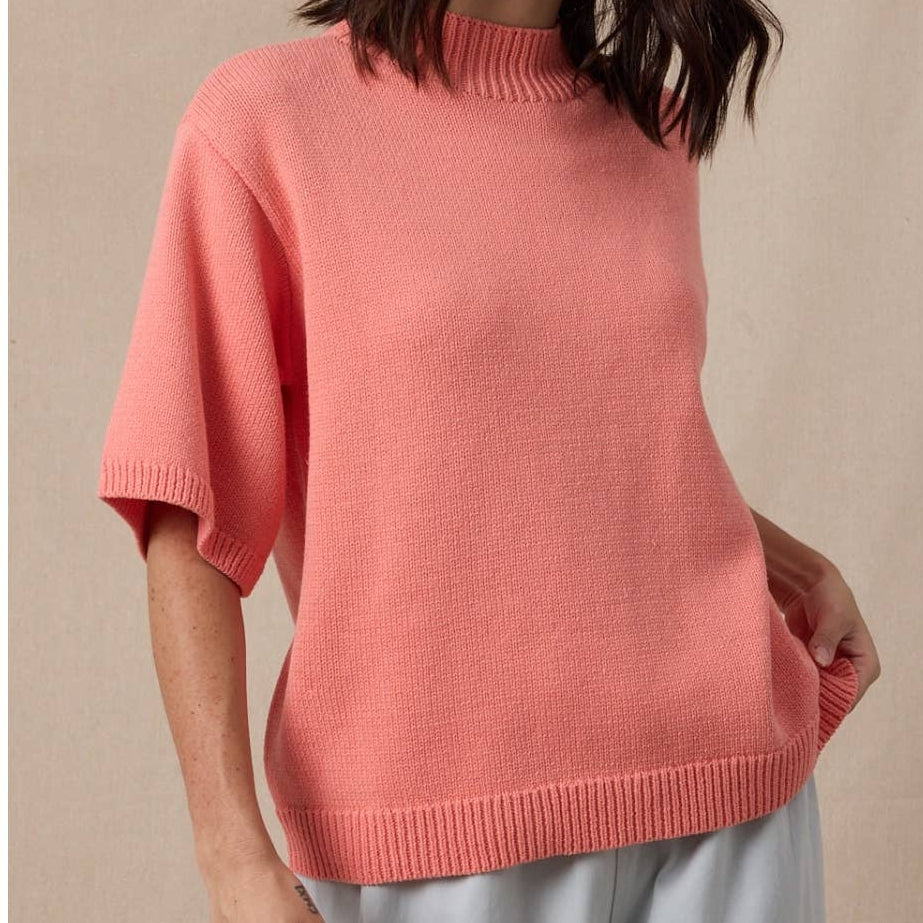 Woman wearing a pink sweater against a beige background
