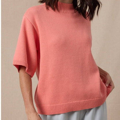 Woman wearing a pink sweater against a beige background