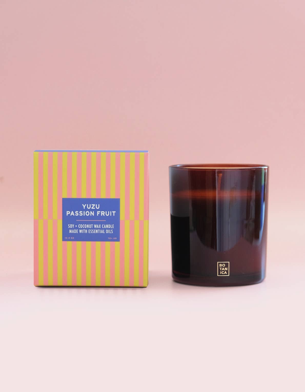 Candle and its packaging with a pink background