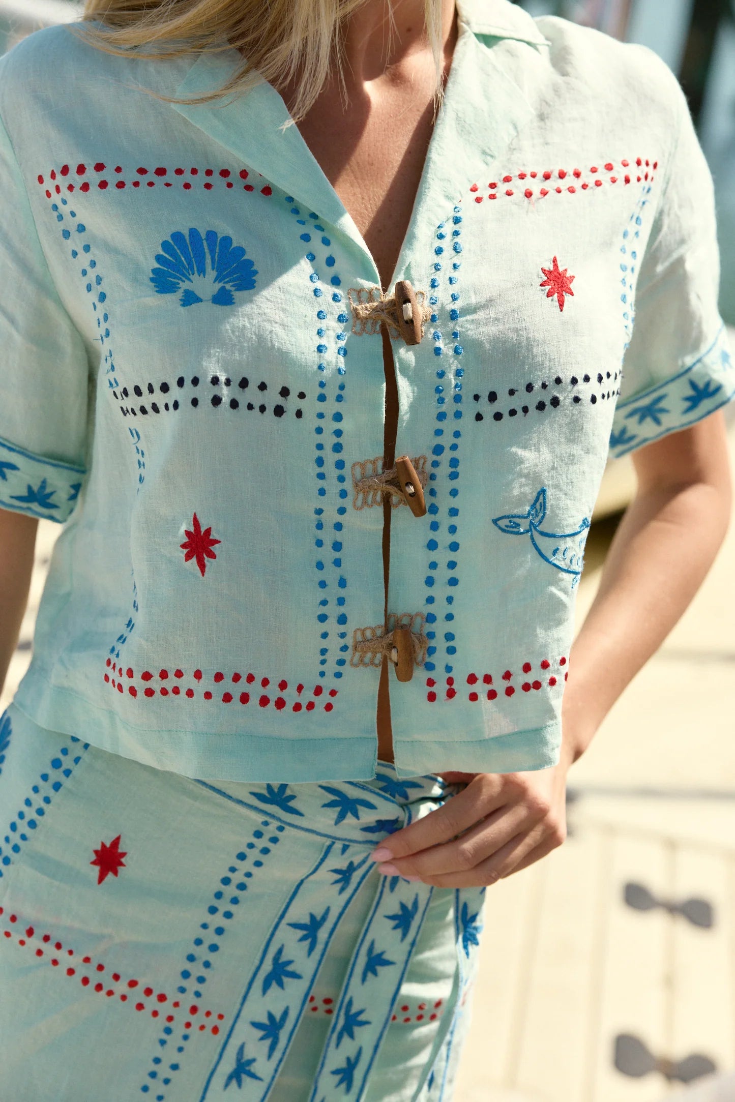 Light blue outfit with red and blue patterns worn by a person.