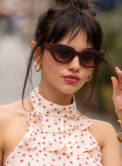 Woman wearing sunglasses and a polka dot top with a blurred background