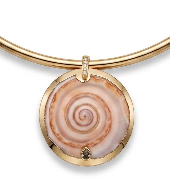 A gold-plated bangle bracelet with a circular pendant featuring a pink and beige spiral seashell design, shown on a plain white background.