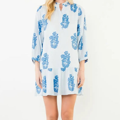 Woman wearing a white dress with blue floral patterns on a white background