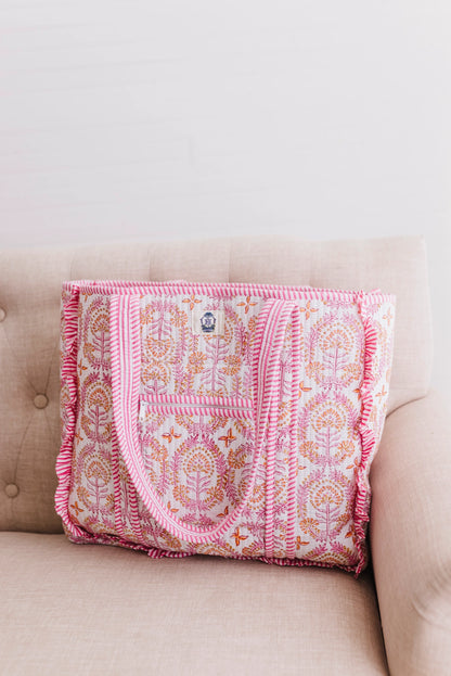 Pink patterned blanket draped over a beige couch