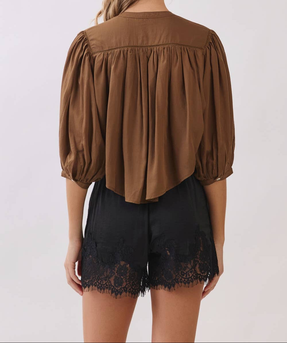 Woman wearing a brown blouse and black lace shorts on a white background
