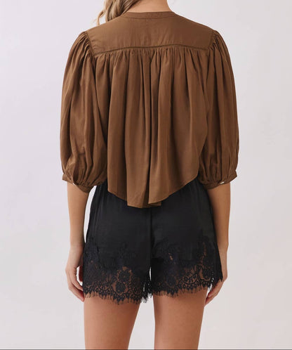 Woman wearing a brown blouse and black lace shorts on a white background