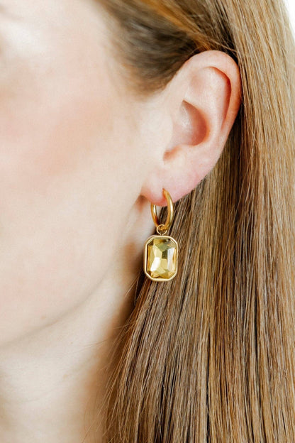 Gold earring worn by a person with blonde hair.