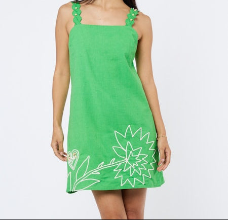 Woman wearing a green dress with white floral design on a plain background