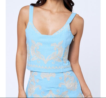 Woman wearing a light blue dress with intricate patterns on a white background