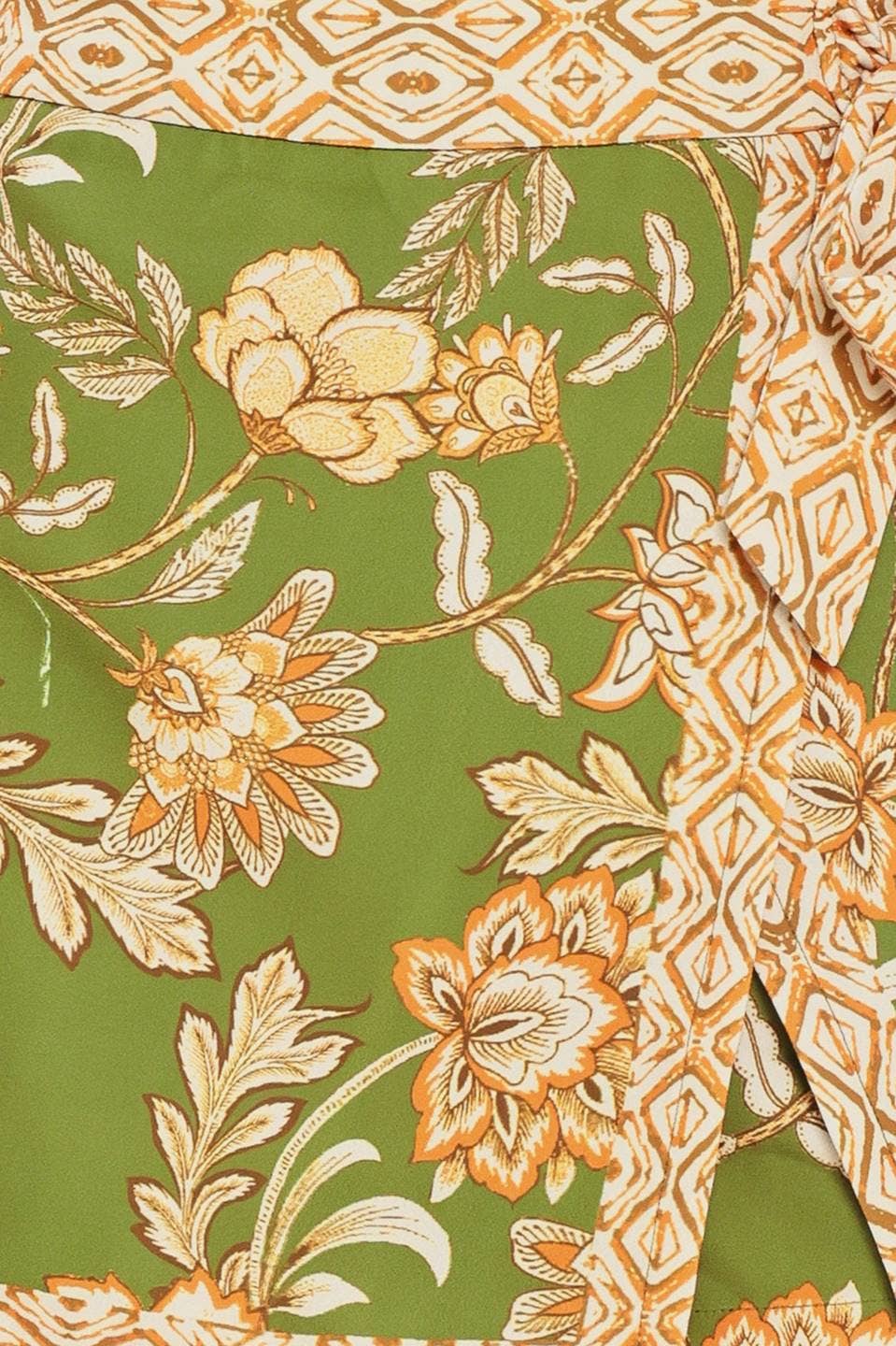 Woman wearing a brown sleeveless top and green floral skirt on a white background